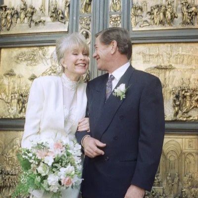 Barbara Eden is wearing all white holding flowers whereas her husband is on a black suit.